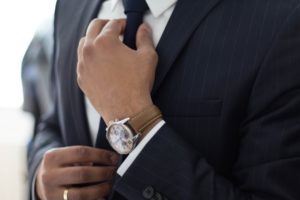 A professional adjusting his tie with a watch on his wrists
